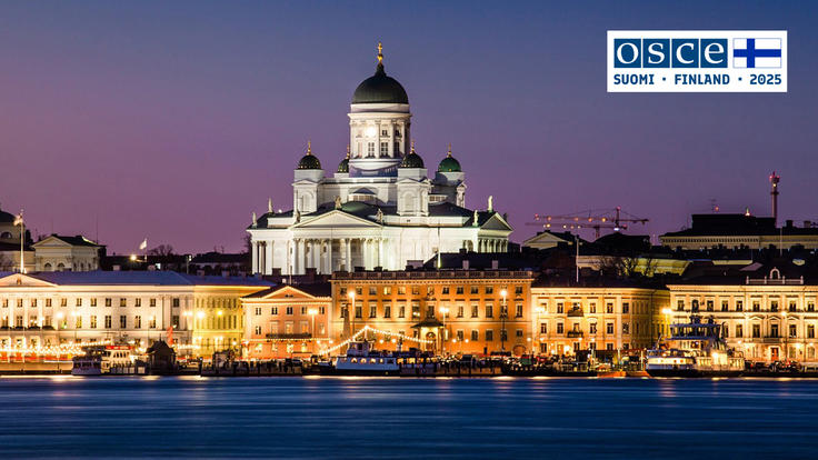 Helsinki Cathedral lit up at dusk, reflecting on the waterfront, under a purple sky.