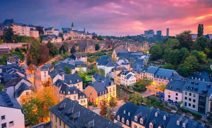 Colorful cityscape at sunset with charming houses, lush greenery, and a vibrant sky.