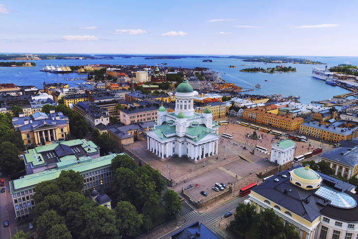 Aerial view of Helsinki Cathedral surrounded by colorful buildings and the harbor against a blue sky.