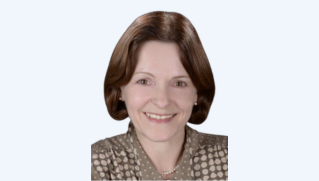 Smiling woman with short brown hair wearing a patterned blouse on a light background.