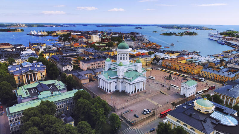 Aerial view of Helsinki Cathedral surrounded by colorful buildings and the harbor against a blue sky.